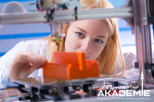 3d-Druck Workshop in den Sommerferien Frau vor einem 3D-Drucker, die sich ein gedrucktes, orangenes Bauteil ansieht.